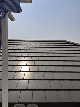 Ouvrier couvreur travaillant sur toiture ardoise d'une maison traditionnelle en pierre